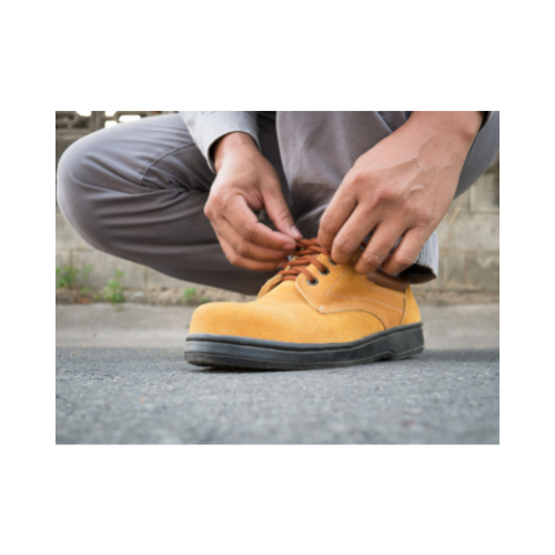 Un travailleur entrain de faire les lacets de ses chaussures de sécurité